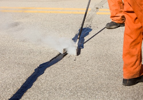 Un hombre utiliza selladores de grietas en venta para reparar la calzada