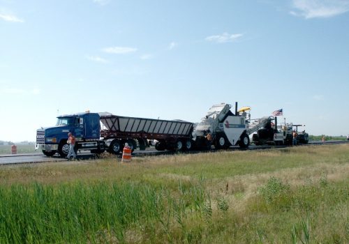 A live bottom trailer and chip spreader working as part of the top-rated chip seal equipment in Texas