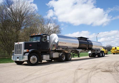 A large tank and truck used to transport liquid asphalt