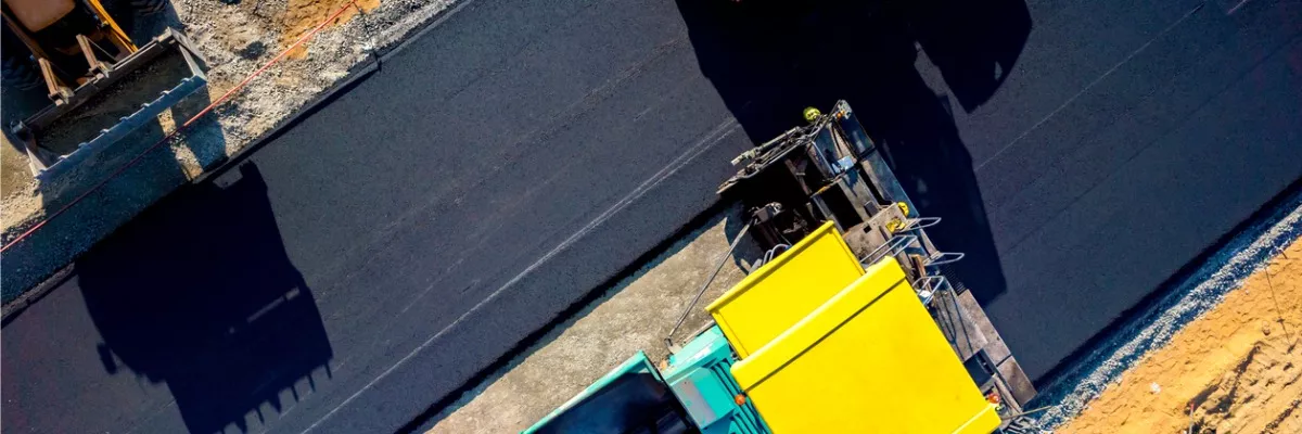 Aerial view of road construction equipment and asphalt being paved
